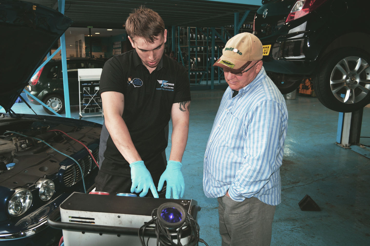 Mechanic helping customer showing car tools