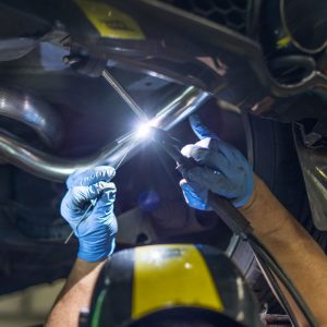 Mechanic welding underneath car